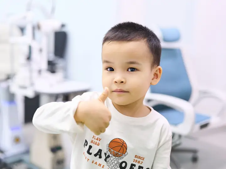 Мальчик в кабинете BABY EYE CLINIC показывает «класс» после проверки зрения