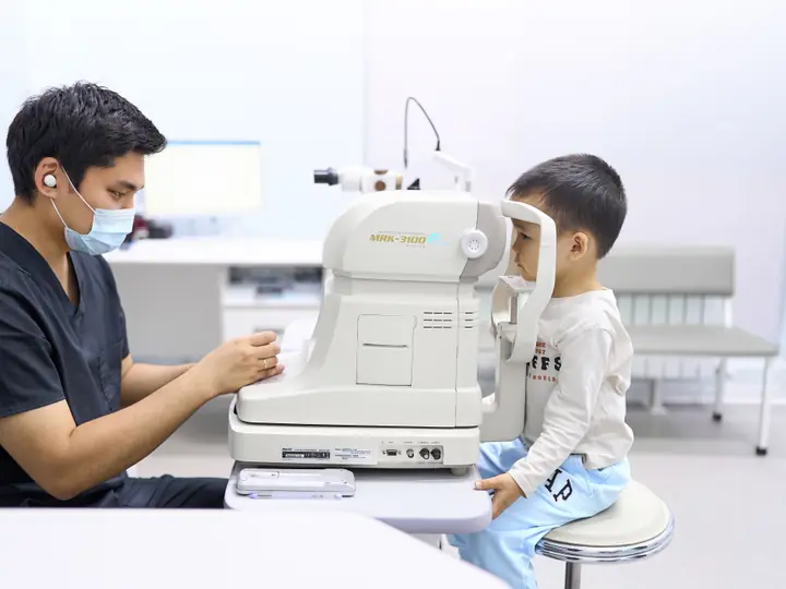 Врач BABY EYE CLINIC проверяет зрение мальчику на приборе, который не касается глаза