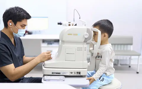Врач BABY EYE CLINIC проверяет зрение мальчику на авторефрактометре