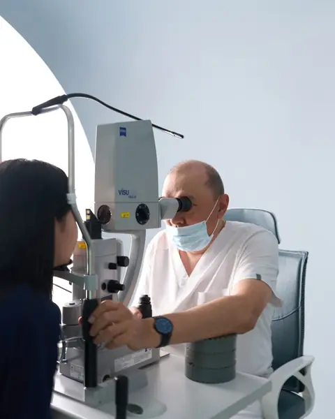Врач RB CLINIC за лазером у щелевой лампы, пациентка сидит у прибора