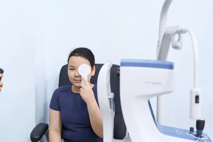 Девочка закрывает один глаз окклюдером, врач BABY EYE CLINIC проверяет второй