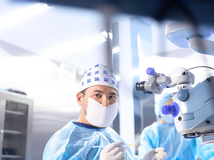 Хирург RB CLINIC в операционной у микроскопа